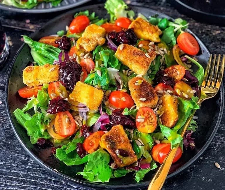 Salad with breaded camembert, cranberries, tomatoes, red onion and honey mustard sauce